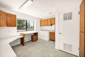 Washroom with cabinet space, a baseboard radiator, washer and clothes dryer, and a desk