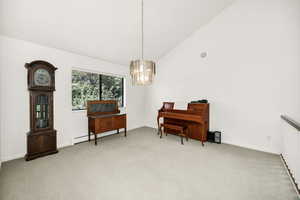Sitting room with a baseboard heating unit, carpet floors, a chandelier, baseboards, and high vaulted ceiling