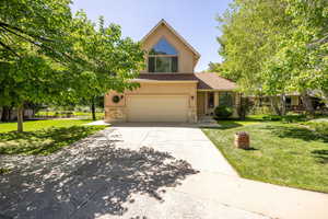 View of front of property featuring stone siding, stucco siding, driveway, and a front yard