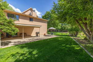 Rear view of property with a patio area, stucco siding, and a chimney