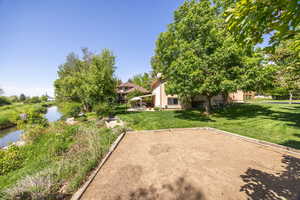 View of grassy yard with a bocce ball area and a water view