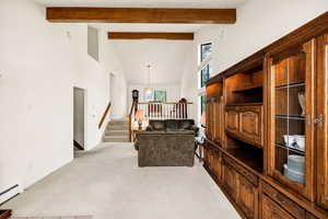 Living area with a baseboard radiator, high vaulted ceiling, light carpet, stairs, and beamed ceiling
