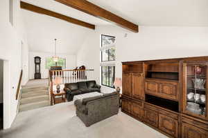 Living room featuring light colored carpet, high vaulted ceiling, beamed ceiling, and plenty of natural light