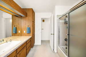 Bathroom with enclosed tub / shower combo, vanity, and baseboards