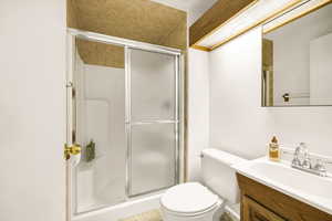 Full bathroom featuring a shower stall, toilet, and vanity