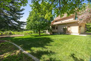 View of green lawn featuring a garage and driveway