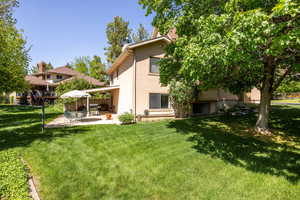 Rear view of property featuring stucco siding, a yard, and a patio