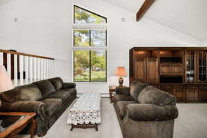 Living room featuring light carpet, high vaulted ceiling, beam ceiling, and a baseboard radiator