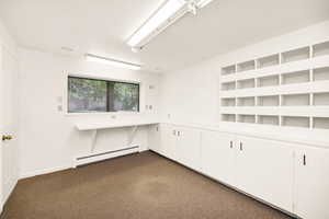 Unfurnished room with a baseboard heating unit and dark colored carpet