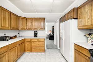Kitchen featuring light countertops, brown cabinets, light floors, and white fridge with ice dispenser