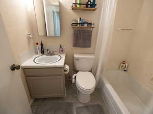 Bathroom with toilet, vanity, tile patterned floors, and shower / bath combo