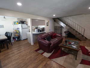 Living room with wood finished floors, stairs, and recessed lighting