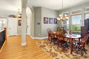 Dining area with arched walkways, light wood finished floors, a chandelier, and baseboards
