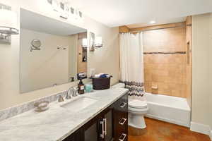 Bathroom with toilet, finished concrete floors, vanity, and shower / tub combo
