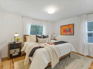 Bedroom with multiple windows, light wood finished floors, and baseboards