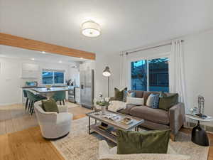 Living area featuring light wood-type flooring, beamed ceiling, baseboards, and recessed lighting
