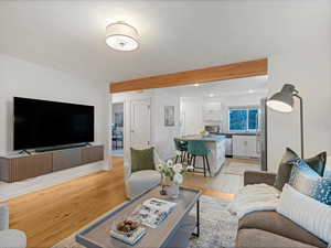 Living area featuring light wood-style floors, beam ceiling, recessed lighting, and baseboards