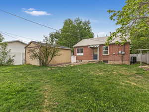 Back of property featuring an outbuilding, brick siding, and central air condition unit