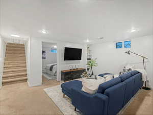 Living area featuring light carpet, stairs, recessed lighting, and baseboards
