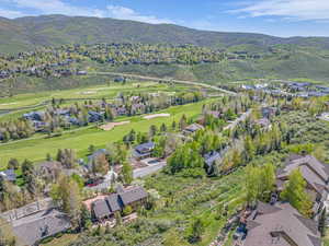 Aerial view of property's location featuring nearby suburban area, a mountain backdrop, and a local golf course
