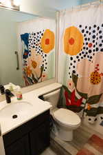 Full bathroom with toilet, vanity, wood finished floors, and curtained shower