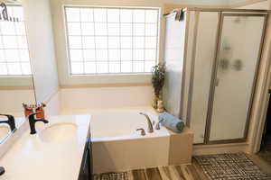 Bathroom with a garden tub, a shower stall, vanity, and wood finished floors