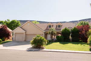 View of front of home with stucco siding, a front yard, concrete driveway, and an attached garage