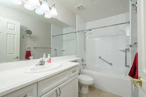 Full bath featuring tile patterned flooring, vanity, toilet, and washtub / shower combination