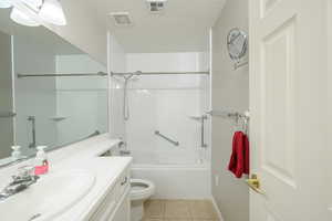 Full bathroom featuring tile patterned floors, toilet, vanity, tub / shower combination, and baseboards