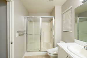 Full bath featuring a shower stall, toilet, tile patterned flooring, and vanity