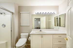 Bathroom with a tile shower, toilet, vanity, and a ceiling fan