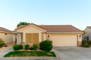 Ranch-style home with concrete driveway, an attached garage, and a tile roof