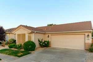 Ranch-style house featuring driveway, a tile roof, an attached garage, and stucco siding