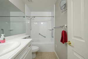 Bathroom featuring toilet, tile patterned floors, vanity, shower / bathtub combination, and baseboards