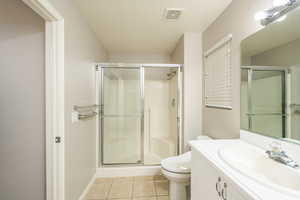 Bathroom featuring a stall shower, toilet, tile patterned flooring, and vanity