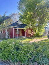 View of front of house with fence, brick siding, a chimney, and a shingled roof
