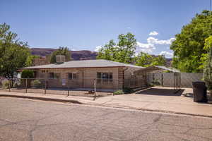 View of front facade featuring a carport, fence, concrete driveway, and a mountain view