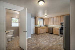 Kitchen with stainless steel appliances, light brown cabinets, light countertops, baseboards, and plenty of natural light