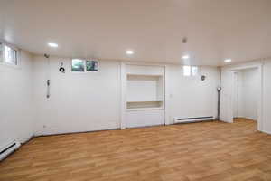 Below grade area with a baseboard heating unit, light wood-style flooring, recessed lighting, and plenty of natural light