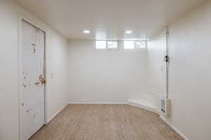Basement featuring light wood-style floors, recessed lighting, heating unit, and baseboards