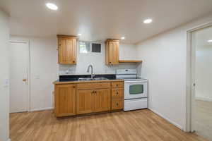 Kitchen with white range with electric cooktop, a sink, light wood-type flooring, baseboards, and recessed lighting