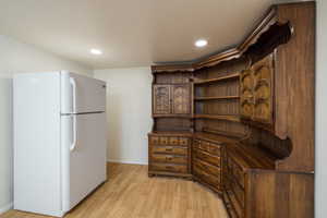 Kitchen featuring freestanding refrigerator, baseboards, dark countertops, open shelves, and light wood finished floors