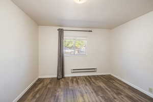 Spare room featuring baseboard heating, wood finished floors, and baseboards