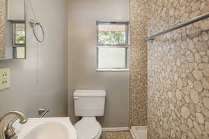 Full bath featuring a sink, toilet, a shower, and baseboards