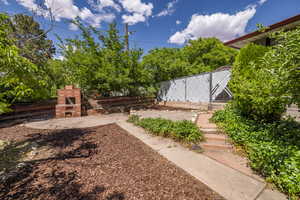 View of yard featuring an outdoor brick fireplace, fence, and a patio