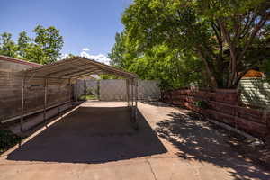 View of parking / parking lot featuring a carport and fence