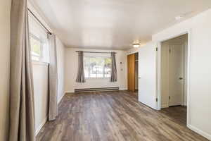 Unfurnished room featuring a baseboard radiator, wood finished floors, a smoke detector, and baseboards