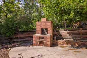 View of patio / terrace featuring an outdoor brick fireplace and fence