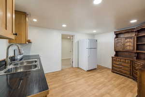 Kitchen with freestanding refrigerator, a sink, light wood-type flooring, recessed lighting, and baseboards
