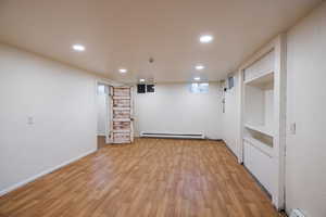 Below grade area with a baseboard radiator, recessed lighting, and light wood-style floors